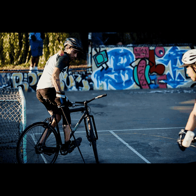 a man riding a bike in front of a wall with graffiti on it that says ' r.p.d. '