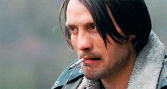 a man with a cigarette in his mouth wearing a denim jacket