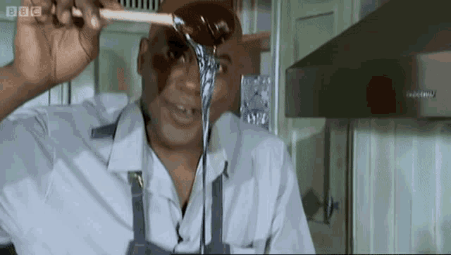 a man is holding a wooden spoon over his head with bbc written on the bottom