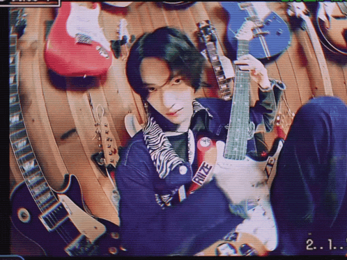 a man holding a guitar with the number 2 on the bottom right