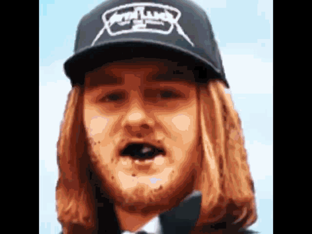 a man with long hair is wearing a black hat with the word metallica on it