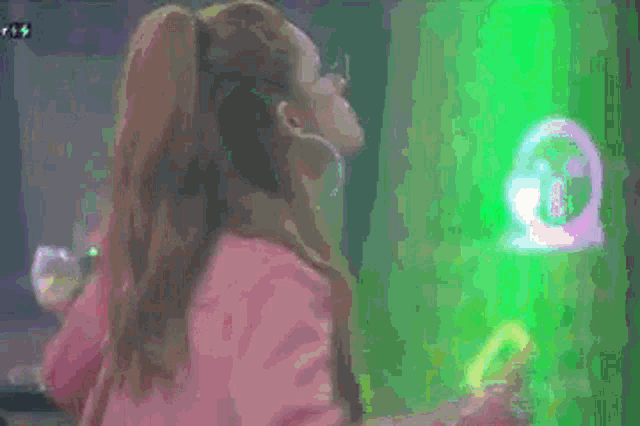 a woman is standing in front of a green light in a dark room .