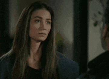 a woman with long hair is looking at a man in a room .