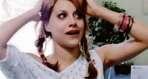 a woman in a hospital gown is holding her hair in pigtails and making a funny face .