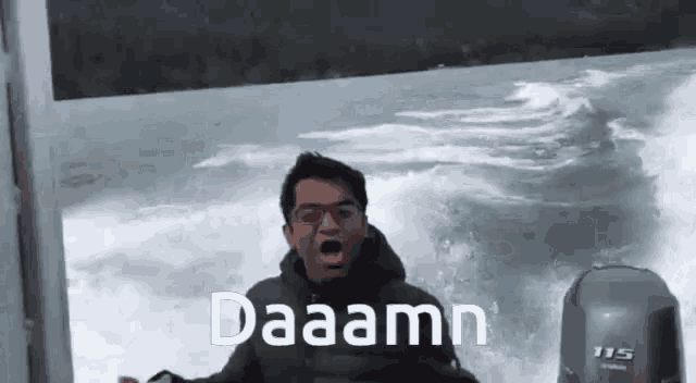 a man is riding on the back of a boat in the ocean and shouting .