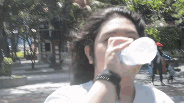 a woman drinking water from a plastic bottle with a blue cap