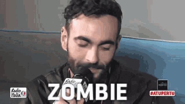 a man with a beard is talking into a microphone and the word zombie is visible