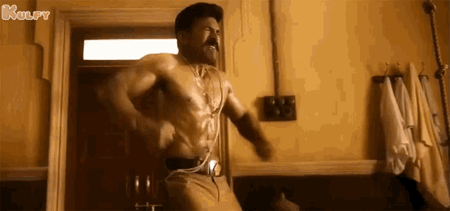 a shirtless man is standing in a bathroom with a towel hanging on the wall .