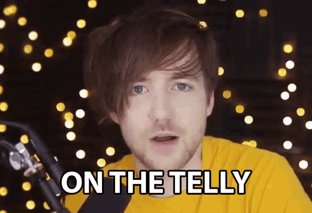 a man in a yellow shirt says on the telly in front of a microphone