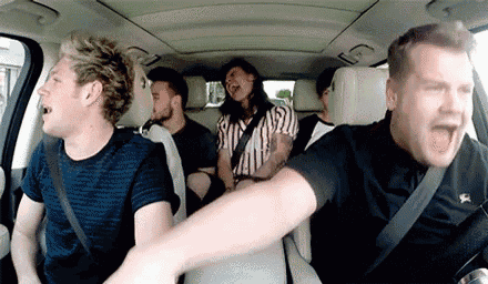 a group of people are sitting in the back seat of a car and laughing .
