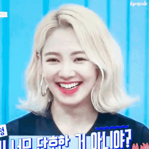 a woman with blonde hair is smiling and wearing hoop earrings and a black shirt .