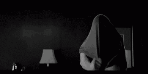 a black and white photo of a shirtless man standing in a room .