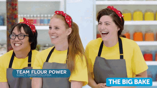 three women wearing aprons and yellow shirts with the words team flour power and the big bake behind them