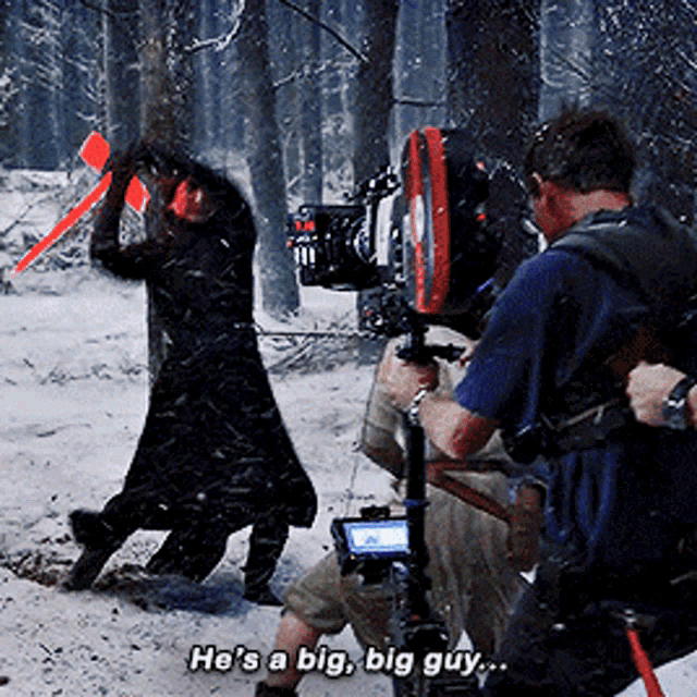 a man holding a camera says he 's a big big guy while another man holds a sword
