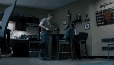 a man wearing a t-shirt that says ' a ' on it is standing in a kitchen