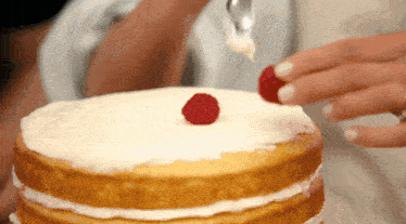 a naked cake with white frosting and a raspberry on top