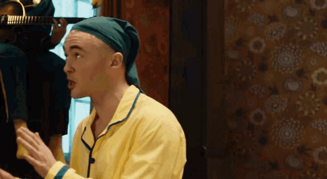 a man wearing a yellow pajamas and a green hat is talking