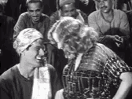 a man and a woman are standing next to each other in front of a crowd of people in a black and white photo .