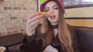 a woman in a pink hat is eating a chicken nugget in a restaurant