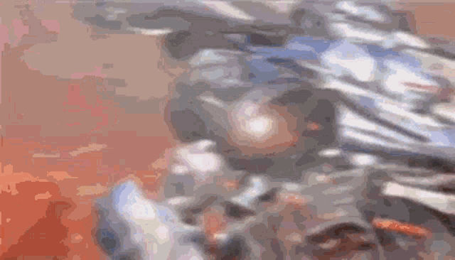 a blurry picture of a robot fighting another robot on a red surface .