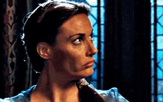 a woman is making a funny face while standing in front of a window in a dark room .
