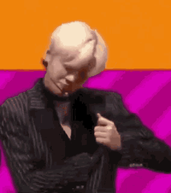 a man in a suit is dancing in front of a colorful background .
