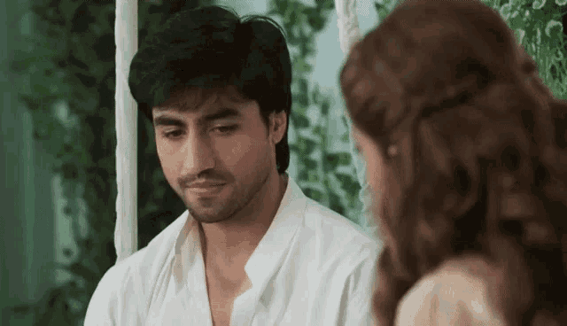 a man in a white shirt is looking down at a woman