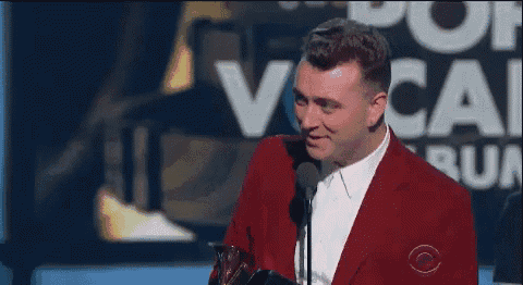 a man in a red suit is giving a speech