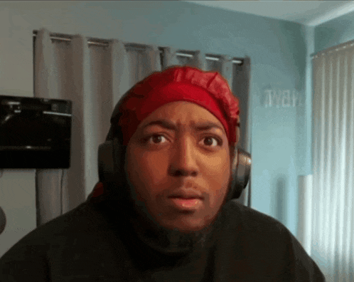 a man wearing headphones and a red head scarf looks surprised