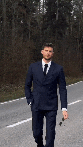 a man in a white tuxedo and black bow tie is walking down the street .