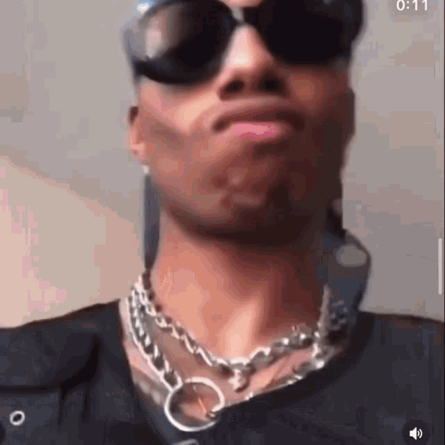 a close up of a person wearing sunglasses and a chain around their neck .