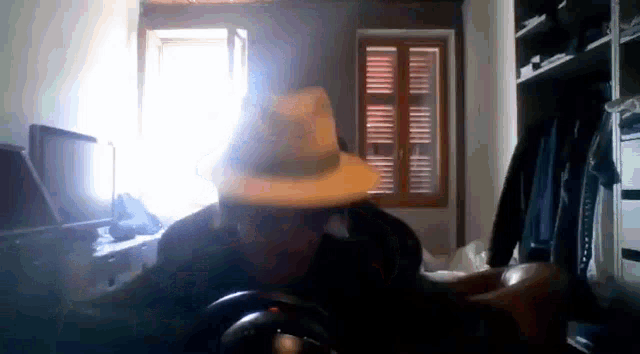 a man in a hat is sitting in front of a window