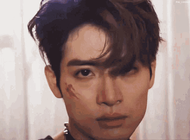 a close up of a young man 's face with a bloody wound on his face .
