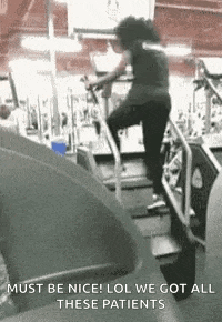 a woman is riding a treadmill in a gym while wearing a mask .