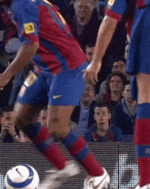 a soccer player is kicking a ball in front of a crowd