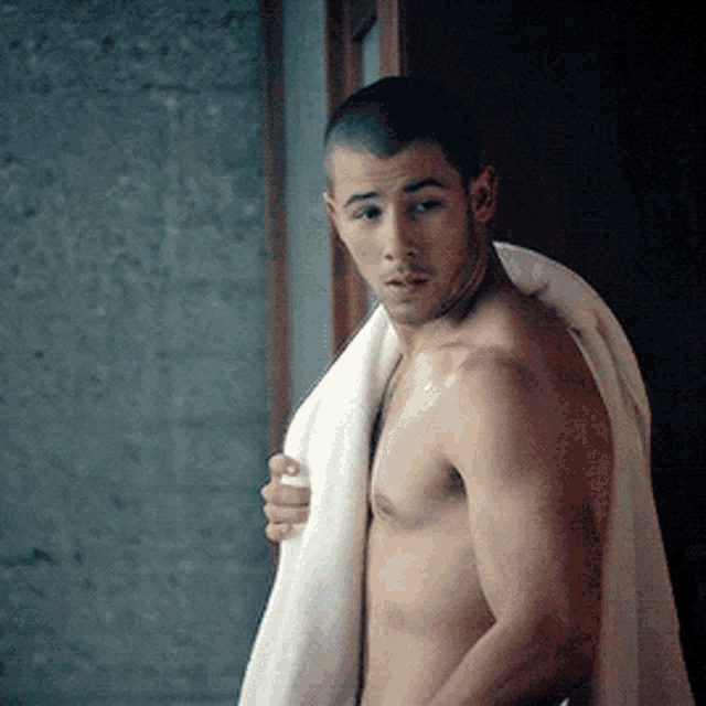 a shirtless man with a towel around his shoulder