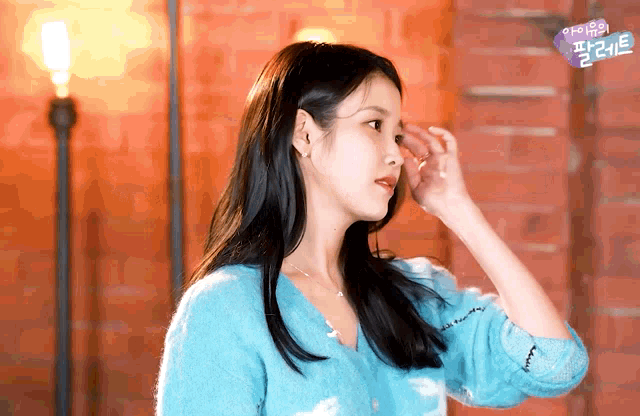 a woman in a blue sweater is standing in front of a red wall