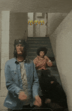 a man in a denim shirt is smoking a cigarette in a staircase