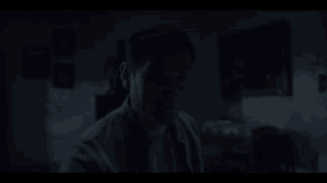 a man is standing in the dark with his eyes closed and his mouth open .