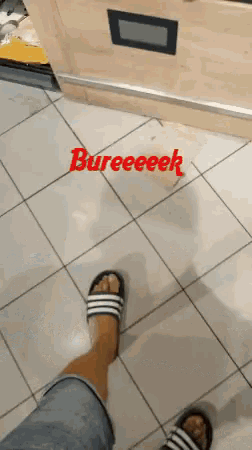 a person standing on a tiled floor with the word bureeeek on the floor