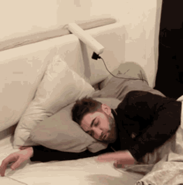 a man is sleeping on a bed with a charger plugged into his head