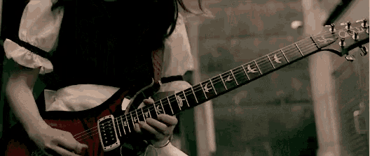a woman is playing a red electric guitar with the letters f and k on the neck