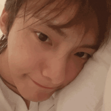 a close up of a woman 's face with a white pillow