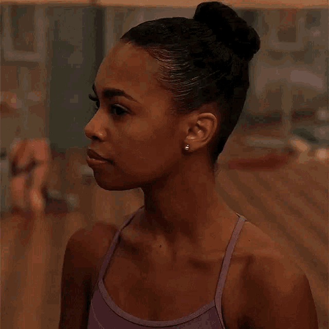 the woman is wearing a purple tank top and earrings .