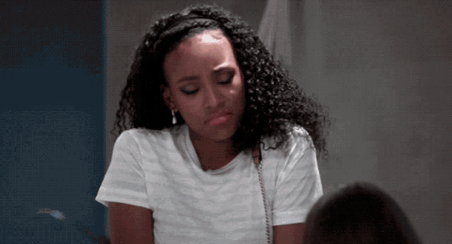 a woman with curly hair is wearing a white shirt and earrings