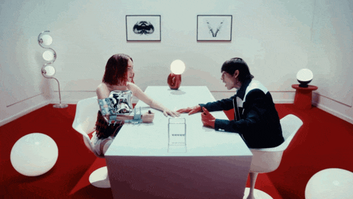 a man and a woman are sitting at a table and the woman is holding his hand