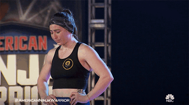 a woman is standing in front of an american ninja warrior sign