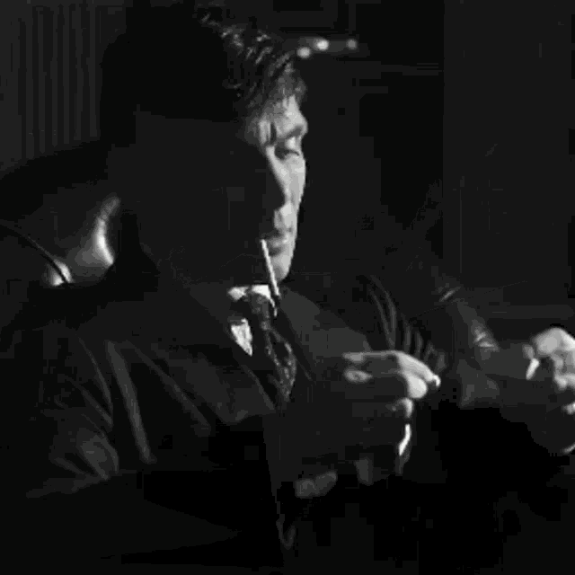 a black and white photo of a man writing with a pen