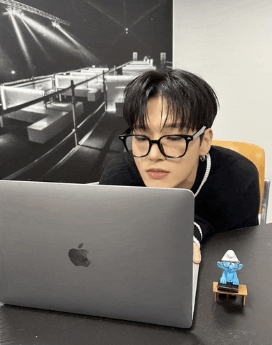 a person wearing glasses looks at an apple laptop