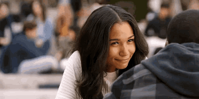 a woman is smiling at a man in a hoodie .